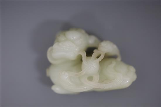 A Chinese pale celadon jade figure of a lion dog and cub, 18th/19th century, L. 6cm, wood stand